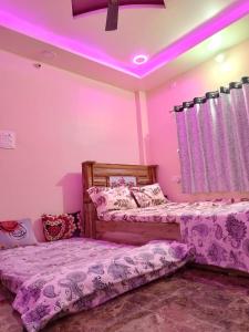 two beds in a room with pink lighting at SHRISHAILAM FARM AND YATRI NIWAS in Akalkot