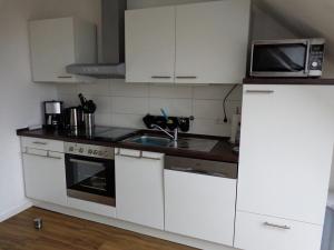 eine Küche mit weißen Schränken und einer Mikrowelle in der Unterkunft Seaside - ABC415 in Wismar