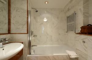 a white bathroom with a tub and a sink at Twenty Nevern Square Hotel in London