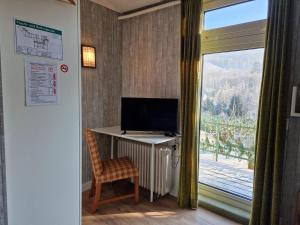 a room with a desk with a computer and a window at Harz Hotel Waldhaus in Goslar