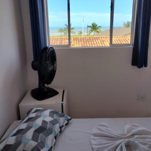 a bedroom with a bed and a window with a fan at Águas Quentes in Caraguatatuba