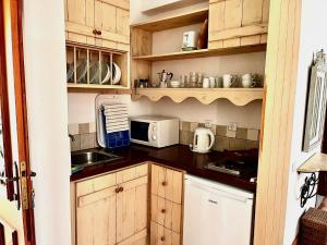 una pequeña cocina con armarios de madera y microondas en Villa Athena Skiathos en Megali Ammos