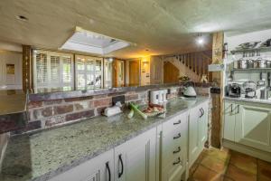 Holme next the SeaにあるThe Old Smithyの白いキャビネットとレンガの壁が備わるキッチン