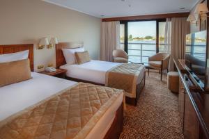 a hotel room with two beds and a television at Jaz Celebrity Nile Cruise - Every Saturday from Luxor for 07 & 04 Nights - Every Wednesday From Aswan for 03 Nights in Luxor