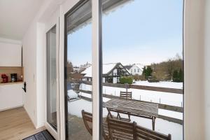 a balcony with a wooden bench and a view of the snow at Ferienwohnung Leineufer in Friedland