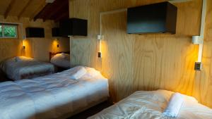 a bedroom with two beds and a tv on the wall at Hostal Central Panguipulli in Panguipulli