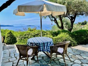 Villa Athena Skiathos في شاطئ ميغالي أموس: طاولة وكراسي تحت مظلة على الفناء
