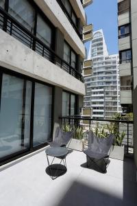 einen Balkon mit 2 Stühlen und einem Tisch auf einem Gebäude in der Unterkunft OWN Belgrano Studios & Suites in Buenos Aires