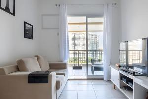 a white living room with a couch and a balcony at Ideal para famílias! Muita segurança in Rio de Janeiro