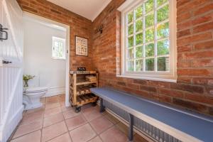 a bathroom with a brick wall and a bench at The Long Cottage in Flitcham