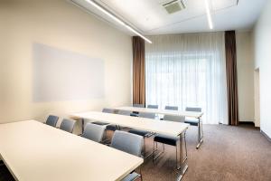 Premier Inn Heilbronn City Centre في هايلبرون: قاعة اجتماعات مع طاولات وكراسي وطاولة بيضاء