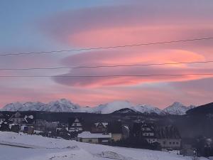 a sunset over a town in the snow with mountains at Domki nad Borem in Male Ciche