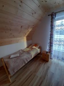 een bed in een kamer met een houten plafond bij Domki nad Borem in Ciche Małe
