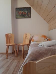 a bedroom with a bed and two chairs at Domki nad Borem in Male Ciche