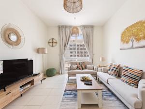 sala de estar con muebles blancos y ventana grande en Brand New 2 Bedroom in La Fontana - 205 en Dubái