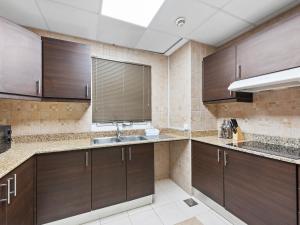 La cuisine est équipée de placards bruns et d'un évier. dans l'établissement Brand New 2 Bedroom in La Fontana - 205, à Dubaï