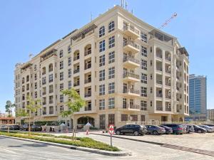 a large building with cars parked in a parking lot at Brand New 2 Bedroom in La Fontana - 205 in Dubai