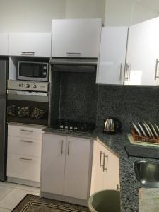 a kitchen with white cabinets and a stove top oven at fox house in Hurghada