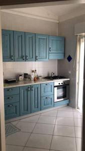 a kitchen with blue cabinets and a white tile floor at Comfort Home in Capoterra +8 photos