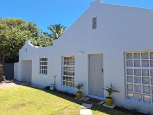 a white house with two plants in the yard at 4 Periwinkle Place in Cape Town