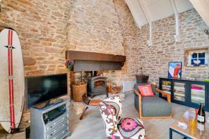 Una sala de estar con una pared de piedra con chimenea. en Escapade dans une belle longere a Penmarch, en Penmarch