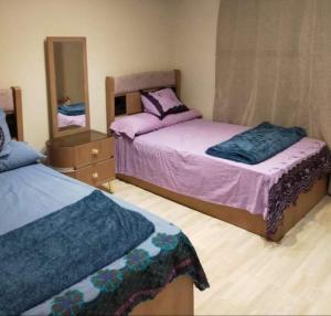 1 dormitorio con 2 camas y espejo en شقه فندقية بالقرب من سيتى ستارز en El Cairo