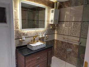 La salle de bains est pourvue d'un lavabo, d'un miroir et d'une douche. dans l'établissement شقه فندقية بالقرب من سيتى ستارز, au Caire