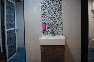 a bathroom with a sink and a tiled wall at mittal dormitory in Mumbai