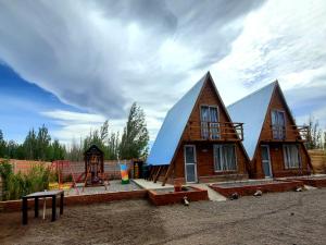 una casa en construcción con un patio de juegos delante de ella en Cabañas alpinas alumine en Perito Moreno