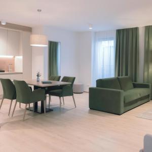 Aparthotel Bad Radkersburg في باد رادكرسبرغ: غرفة معيشة مع طاولة وكراسي خضراء