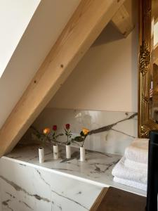 un baño con flores en jarrones sobre una encimera de mármol en Le Hameau de la Closerie 