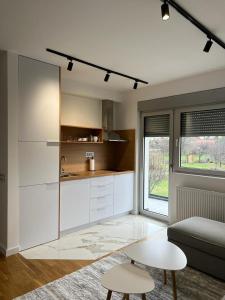 a kitchen with white cabinets and a table and a couch at Vulkan LUX apartments in Zemun