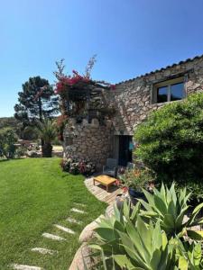 a stone house with a garden in front of it at Hôtel Ambassador Palombaggia in Porto-Vecchio