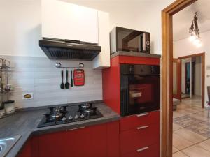 a kitchen with red cabinets and a stove top oven at Appartamento a 20 minuti dal Centro, Zona Residenziale Tranquilla, Free Parking, 2 Camere, 5 posti letto in Turin