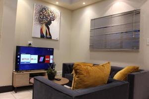 a living room with a couch and a television at Cosy Apartment in Johannesburg in Johannesburg