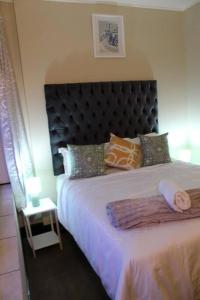 a bedroom with a large bed with a black headboard at Cosy Apartment in Johannesburg in Johannesburg