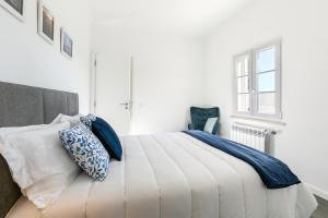 um quarto branco com uma cama com almofadas azuis em Casa Avós Félix Lopes na Foz do Arelho