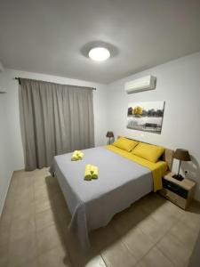 a bedroom with a large bed with yellow pillows at CENTRAL APARTMENT PORTOHELI 1 in Porto Heli