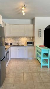 a kitchen with white cabinets and a blue table at CENTRAL APARTMENT PORTOHELI 1 in Porto Heli +14 photos
