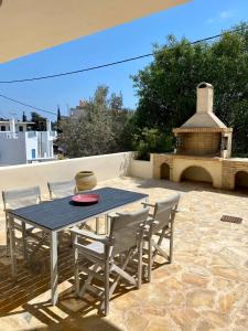 a table and chairs on a patio with a fireplace at CENTRAL APARTMENT PORTOHELI 1 in Porto Heli