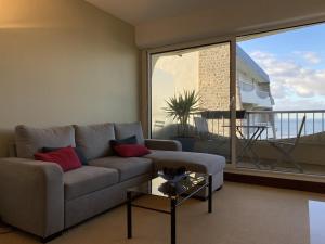 Una sala de estar con un sofá y una ventana grande. en 471 - Appartement T2 avec terrasse pleine vue mer, en Erquy