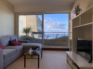 Una sala de estar con un sofá y una ventana grande. en 471 - Appartement T2 avec terrasse pleine vue mer, en Erquy