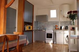een keuken met witte apparatuur en een tafel met een tafel bij 480 - Maison de pêcheur à 50m de la Plage de Caroual 