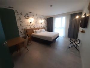 a hotel room with a bed and a window at L'Escale Marine, The Originals Relais in Crozon