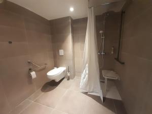 a bathroom with a toilet and a shower with a shower curtain at L'Escale Marine, The Originals Relais in Crozon