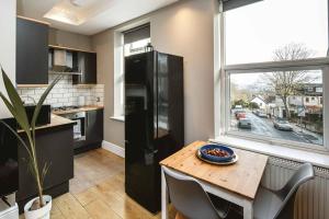 uma cozinha com uma mesa e um frigorífico preto em Crystal Palace 2 Bedroom Flat em Crystal Palace