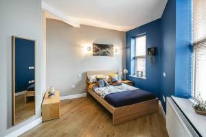 1 dormitorio con paredes azules y 1 cama con almohadas en Crystal Palace 2 Bedroom Flat, en Crystal Palace