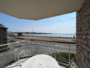 uma varanda com uma mesa e vista para o oceano em 504 - A Erquy, en bordure de la plage du centre, à 800m des commerces em Erquy