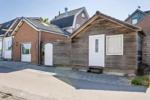 uma casa de madeira com portas brancas numa rua em SéSé em Vinkeveen