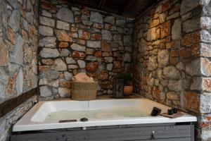 a large bath tub in a stone walled bathroom at Unedo All Seasons Hotel in Palaios Panteleimonas